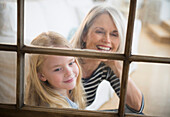 Senior Caucasian woman and granddaughter looking out window, Jersey City, New Jersey, USA