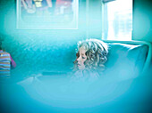 Curly-haired girl sitting on sofa