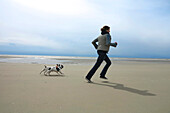 women runnig on the beach with her dogs