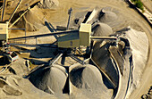 aerial view of a career. Details of a machine. Around them several mounds of gravel