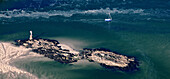 aerial view of a sailboat on the ocean. Rocks in the foreground and tag