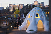 'An igloo sculpture and building illuminated at dusk; London, England'