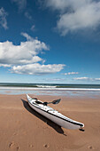 'Northumberland, England; A Kayak Sitting On The Sand On Low Newton Beach'
