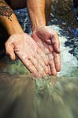 'Hands Touch The Cascade Of Water At Currumbin Rock Pools In Currumbin Valley; Gold Coast, Queensland, Australia'