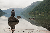 'A Young Man Sits On A Rock In Cameron Lake; British Columbia Canada'