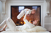 'Mother And Baby On Carpet In Front Of Fireplace; Jordan, Ontario, Canada'