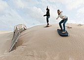 'Young Women Slide On Boards Over The Punta Paloma Sand Dunes; Tarifa, Cadiz, Andalusia, Spain'