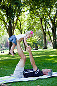 'Father Lifting Daughter Up On His Legs In The Park; Edmonton, Alberta, Canada'