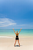 'A Woman Tourist Standing With Arms Raised On A Tropical Island; Koh Lanta, Thailand'