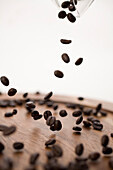 Coffee Beans Dropping Onto Wooden Plate