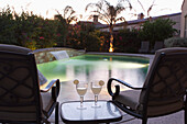'Pool Side Setting At Dusk With Pool Lights Two Chairs Table And Two Glasses With Lime Wedges; Palm Springs, California, United States of America'