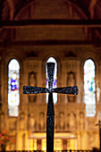 'A Black Cross With Stained Glass Windows In The Background; Bamburgh, Northumberland, England'