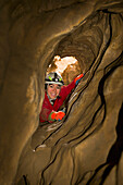 'A Woman Looks Through A Hole In A Cave; Canmore, Alberta, Canada'