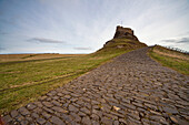 'A Cobblestone Path With A Building In The Distance; Lindisfarne, Northumberland, England'