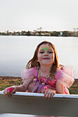 'A young girl wearing a pink dress and accessories at the water's edge;Gold coast queensland australia'