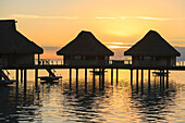 'Silhouette of huts over the water at sunset at the bora bora nui resort & spa;Bora bora island society islands french polynesia south pacific'