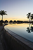 'Sunset and palm trees reflecting in a pool at the bora bora nui resort and spa;Bora bora island society islands french polynesia south pacific'