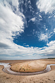 'A stream formed in a circular shape in the sand along the coast;Druridge bay northumberland england'