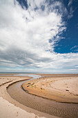 'A stream formed in a circular shape in the sand along the coast;Druridge bay northumberland england'