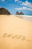 'View of morro dos irmaos from praia do bode with brazil written in the sand;Fernando de noronha pernambuco brazil'