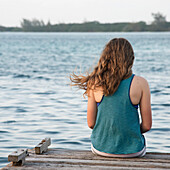 'A Girl Sits On The Edge Of A Dock; Utila, Bay Islands, Honduras'