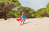 'A woman walking on the beach and smiling at the camera; Tarifa, Cadiz, Andalusia, Spain'