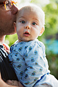 'Father holds and kisses young baby boy; Toronto, Ontario, Canada'