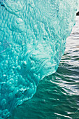 'Iceberg broken off Mendenhall Glacier floating in Mendenhall lake, flipping over and exposing blue polished ice from being underwater; Juneau, Alaska, United States of America'