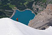 Mountaineer during descent of Blümlisalp (3661 m), Oeschinensee in the background, Bernese Alps, Switzerland