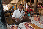 Butcher sharpening a knife at a market stand, Nosy Be, Madagascar