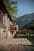 Mann und Frau genießen Ausblick von Balkon auf Bohinjer See und umliegende Alpen, Bohinj bei Bled, Slowenien, Europa