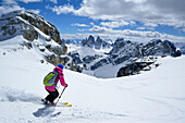 Female back-country skier downhill skiing from Hochebenkofel, Sexten Dolomites, South Tyrol, Italy
