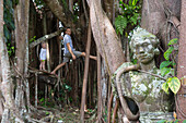 Banyan tree, sculpture, Balinese temple dancer, father and son climbing in the tree, garden of the art museum, Museum Puri Lukisan, tropical vegetation, boy 3 years, jungle, western family, Germans, family travel in Asia, parental leave, MR, Ubud, Bali, I