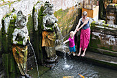 Mother, son, playing with water, Balinese sculptures, well, pool, at the elefantÄs cave, Goa Gajah, 3 year old boy, western family, family travel in Asia, parental leave, MR, Ubud, Bali, Indonesia