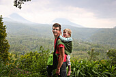 Father hiking with his son, boy 3 years old in a wrap on his back, forest, walking, parental leave, Munduk, Bali, Indonesia