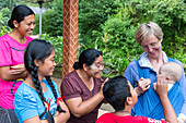 Balinese family playing with German baby, wrap, baby sling at her mother, baby 5 months old, intercultural contact, meeting local people, locals, family travel in Asia, parental leave, German, European, MR, Munduk, Bali, Indonesia