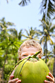 Kleiner Junge hält große Kokosnuss, Palmen, lachen, Kokosmilch, Junge 3 Jahre, Ferien, Elternzeit in Asien, Europäer, Deutsche, Westler, Familie, MR, Gili Air, Gili Inseln, Lombok, Indonesien