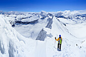 Skitourengeherin steht am Schneegrat des Großen Möseler, Schwarzenstein, Dritte Hornspitze und Turnerkamp im Hintergrund, Zillertaler Alpen, Südtirol, Italien