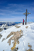 Woman standing beside summit cross of Birkkarspitze, Karwendel range, Tyrol, Austria