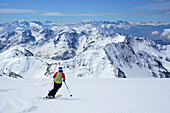 Frau auf Skitour fährt vom Hohen Weißzint ab, Dolomiten im Hintergrund, Zillertaler Alpen, Südtirol, Italien