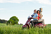 Ein Mann und eine Frau transportieren mit einem roten Vespa Roller einen Stapel Bücher, Odershausen, Bad Wildungen, Nordhessen, Hessen, Deutschland, Europa