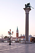 The big pillar with the winged lion of San Marco and view of Isola di San Maggiore island with Chiesa di San Maggiore church at sunrise, Venice, Veneto, Italy, Europe