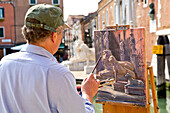 An artist painting the lion sculptures at the Arsenale, Venice, Veneto, Italy, Europe