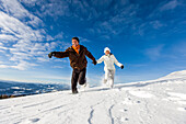 Couple running through snow, Zirbitzkogel, Muehlen, Styria, Austria