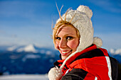 Young woman wearing a cap smiling at camera, Kreischberg, Murau, Styria, Austria