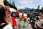 Kellnerin serviert Bier auf einer Terrasse einer Skihütte, Planai, Schladming, Steiermark, Österreich