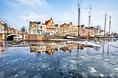 Buildings in Harleem reflecting in the half-frozen Spaarne River, about 20 km from Amsterdam, Holland, Netherlands