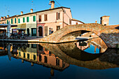 An old bridge reflexed in the canal at Comacchio, Emilia Romagna, Italy