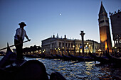 A gondolier navigates just offshore of Venice, Italy, at night.