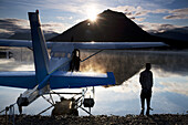 A man stands next to a float plane in Twin Lakes in Lake Clark National Park, Alaska.